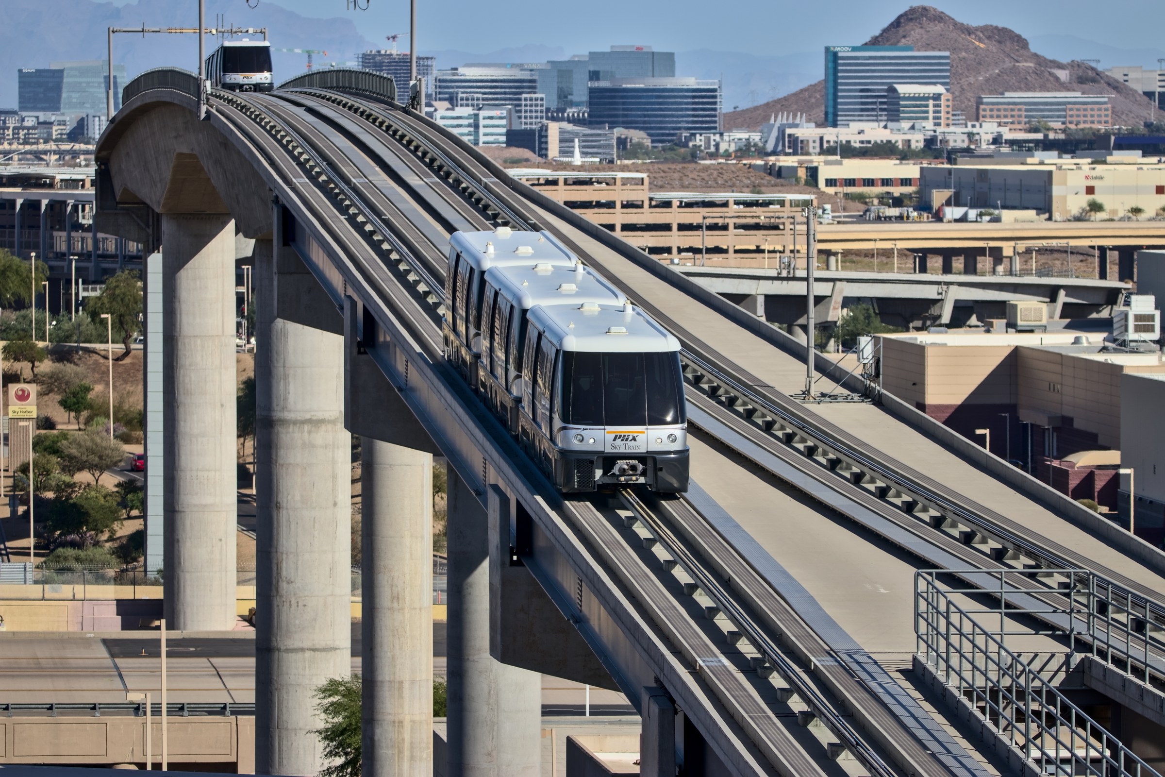 Photograph of a PHX Sky Train automated people mover vehicle at the Terminal 4 station in October 2023, with the elevated guideway and station platform