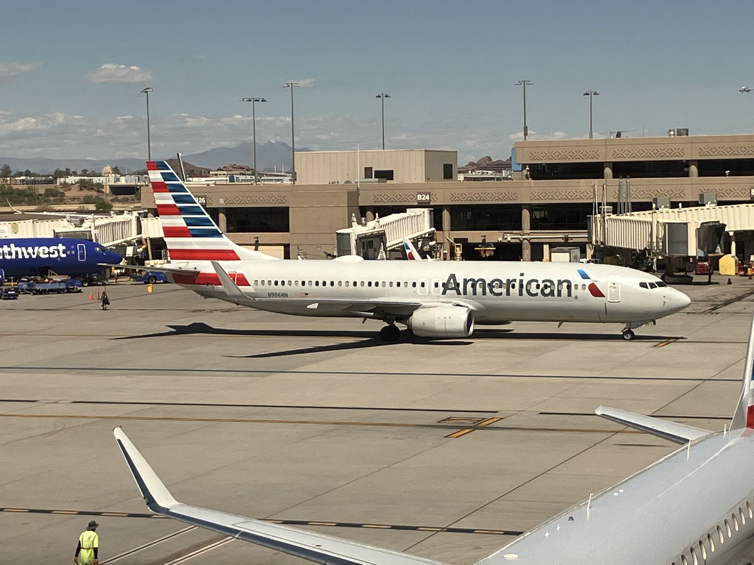 Photograph of an American Airlines Boeing 737 parked at Terminal 4 gate B22 in May 2025, seen from the apron with the jet bridge attached