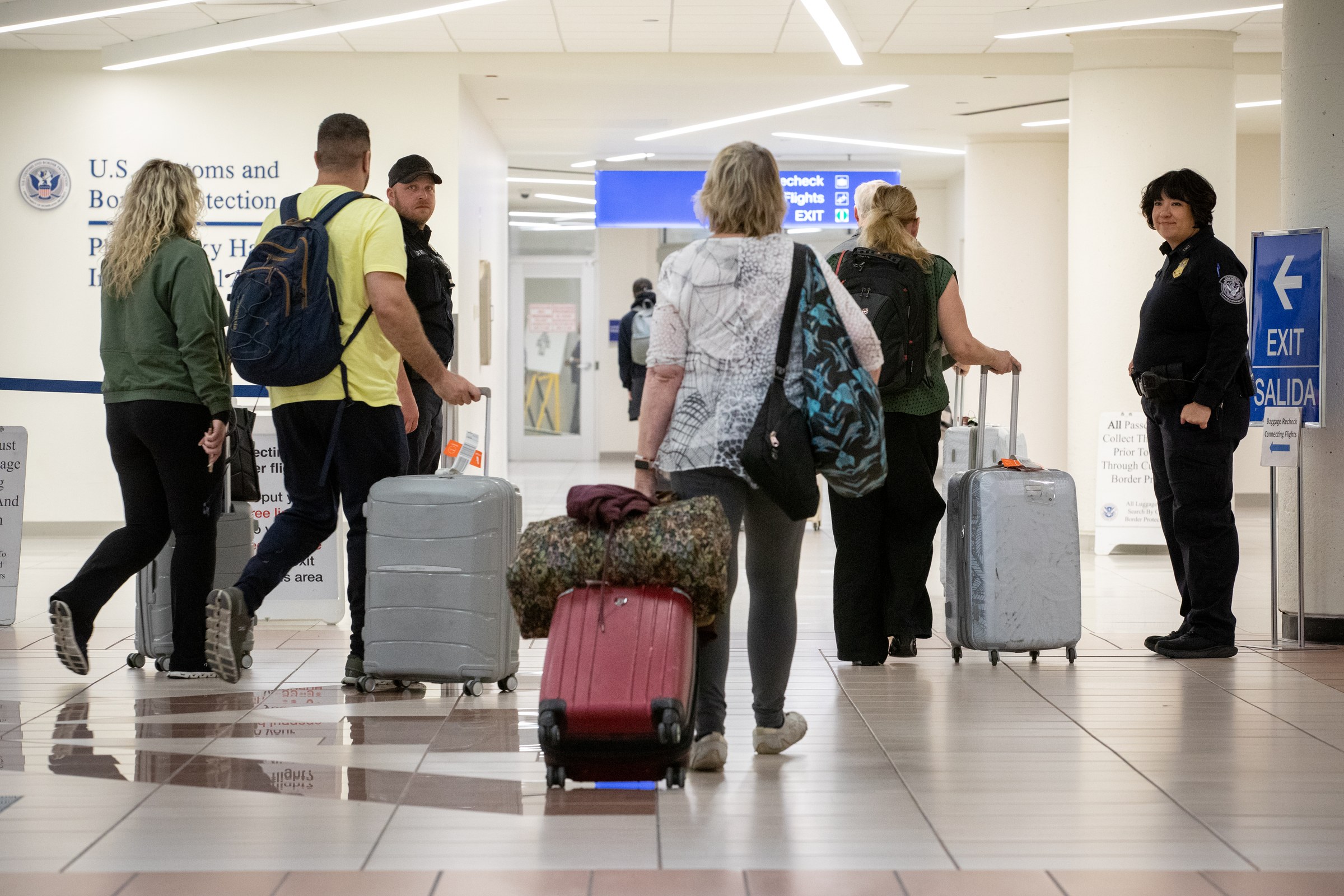Photograph of U.S. Customs and Border Protection officers directing arriving international passengers in the Terminal 4 international arrivals baggage claim area in December 2024