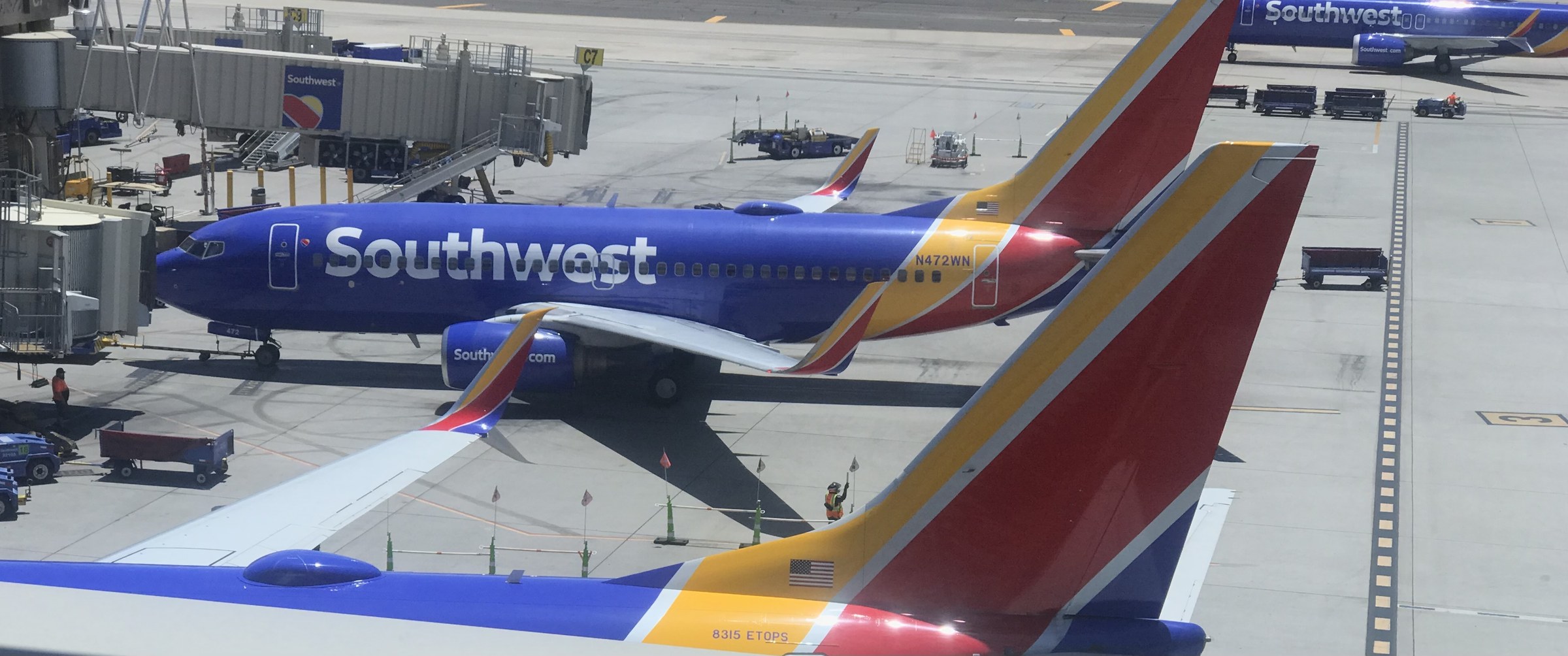 Photograph of a Southwest Airlines Boeing 737 on the Terminal 4 apron at Phoenix Sky Harbor in July 2025, with the concourse and jet bridges behind